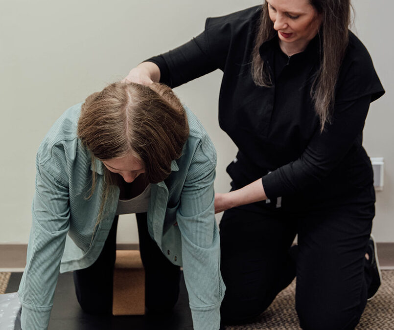 Physical therapist helping a postpartum patient improve upper back and rib mobility
